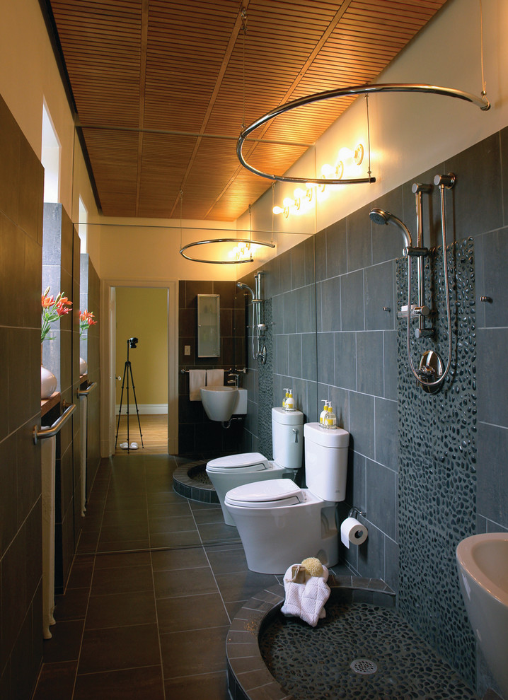 На фото: ванная комната в современном стиле с подвесной раковиной, открытым душем, раздельным унитазом, серой плиткой, галечной плиткой и шторкой для ванной