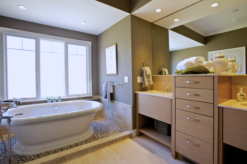 Ispirazione per una stanza da bagno classica con lavabo sottopiano, ante lisce, ante in legno chiaro, vasca freestanding, piastrelle di ciottoli e pavimento in marmo