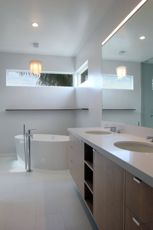 Inspiration pour une salle de bain principale design en bois foncé de taille moyenne avec un placard à porte plane, une baignoire indépendante, un mur blanc, un sol en carrelage de porcelaine, un lavabo encastré, un plan de toilette en surface solide et un sol blanc.