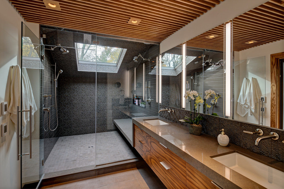 Design ideas for a contemporary bathroom in Chicago with flat-panel cabinets, medium wood cabinets, an alcove shower, black tiles, white walls, a submerged sink, grey floors, a hinged door, grey worktops and double sinks.