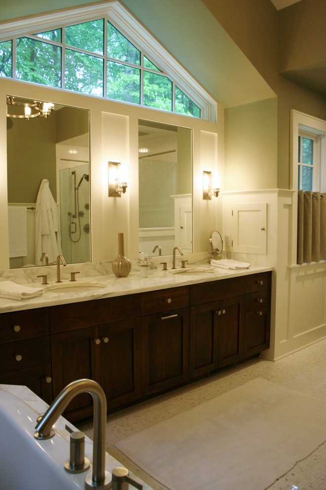 На фото: главная ванная комната среднего размера в современном стиле с фасадами в стиле шейкер, темными деревянными фасадами, угловым душем, раздельным унитазом, белой плиткой, белыми стенами, полом из керамогранита, врезной раковиной, мраморной столешницей и ванной в нише