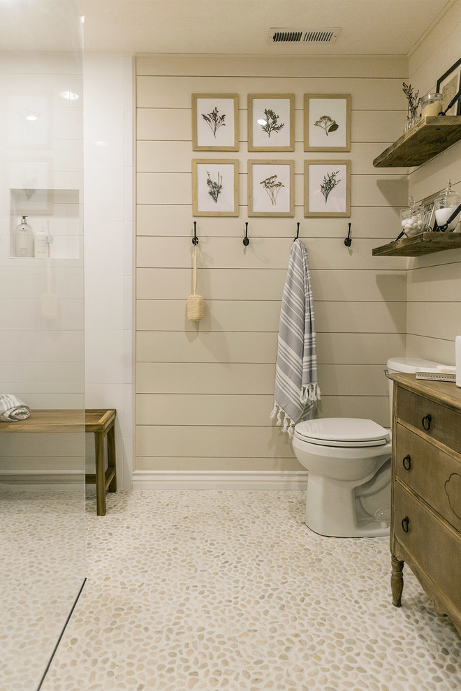 Medium sized farmhouse ensuite bathroom in Tampa with medium wood cabinets, a double shower, white tiles, pebble tiles, beige walls, pebble tile flooring, a vessel sink, beige floors and an open shower.