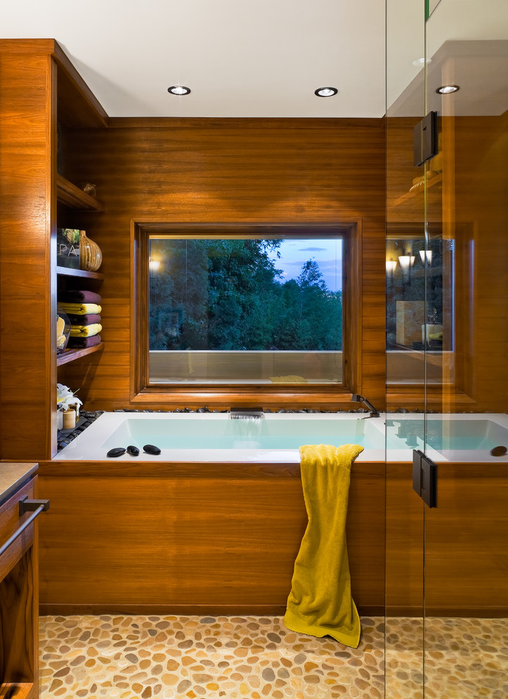 Cette photo montre une grande salle de bain principale tendance avec une baignoire en alcôve, une douche d'angle, des carreaux de béton, un mur marron, un sol en galet, un sol beige et une cabine de douche à porte battante.