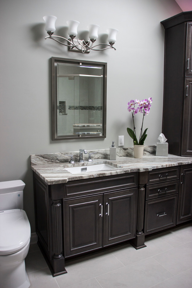 Exempel på ett mellanstort klassiskt en-suite badrum, med luckor med upphöjd panel, grå skåp, ett fristående badkar, en hörndusch, en toalettstol med hel cisternkåpa, vit kakel, porslinskakel, grå väggar, klinkergolv i porslin, ett undermonterad handfat och granitbänkskiva