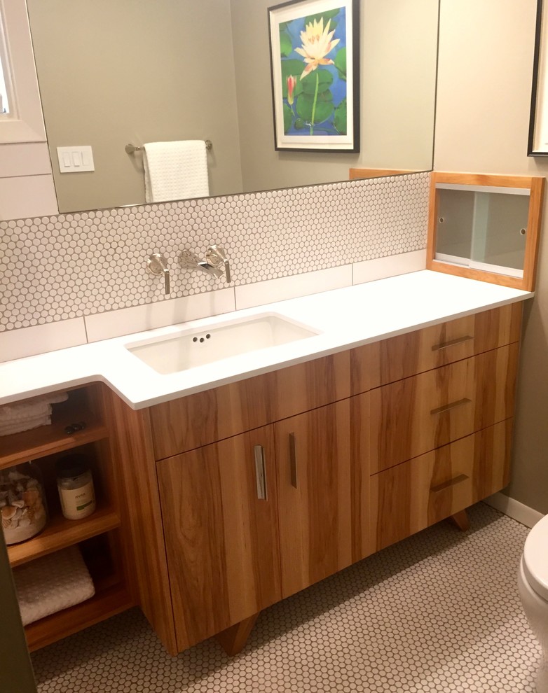 Small modern ensuite bathroom in Austin with freestanding cabinets, medium wood cabinets, a built-in bath, a shower/bath combination, a one-piece toilet, white tiles, porcelain tiles, beige walls, porcelain flooring, a submerged sink and solid surface worktops.