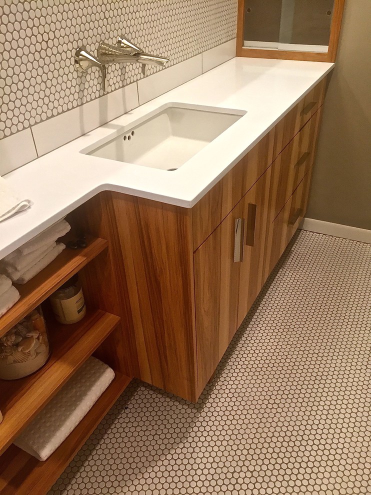 Design ideas for a small modern ensuite bathroom in Austin with freestanding cabinets, medium wood cabinets, a built-in bath, a shower/bath combination, a one-piece toilet, white tiles, porcelain tiles, beige walls, porcelain flooring, a submerged sink and solid surface worktops.