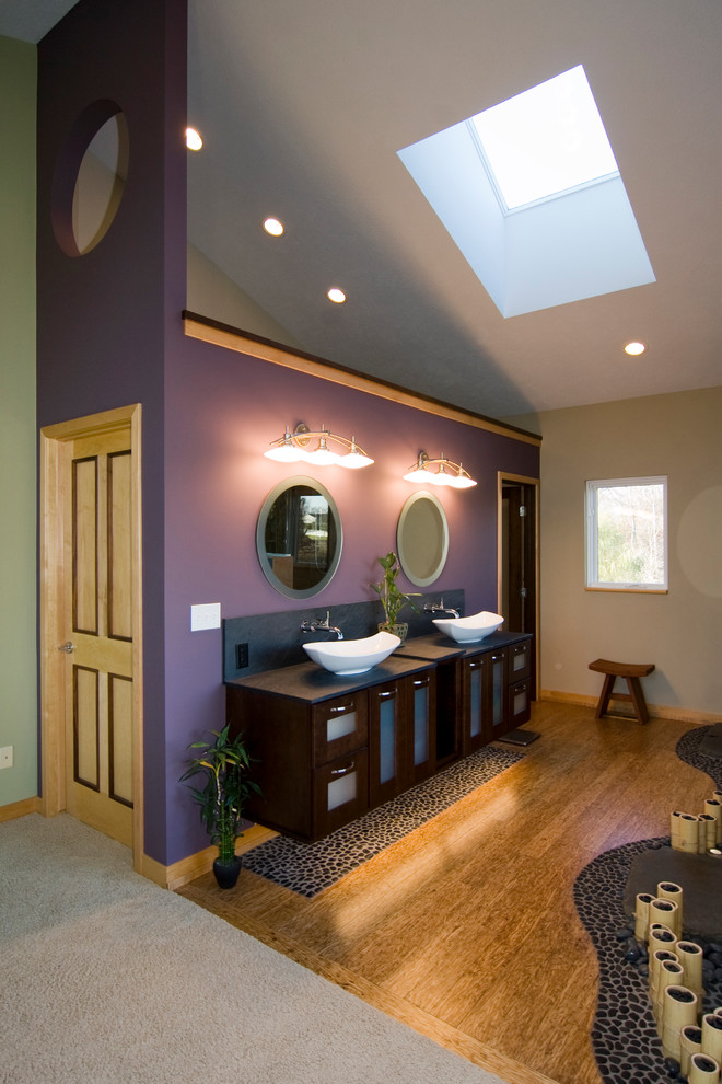 Пример оригинального дизайна: большая главная ванная комната в восточном стиле с настольной раковиной, фиолетовыми стенами, стеклянными фасадами, темными деревянными фасадами и паркетным полом среднего тона