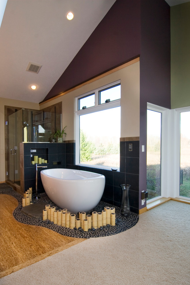 Foto de cuarto de baño principal asiático grande con bañera exenta, baldosas y/o azulejos grises, paredes púrpuras y suelo de madera clara