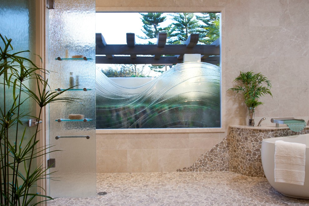 Cette photo montre une grande salle de bain principale tendance en bois brun avec une baignoire indépendante, une douche ouverte, une plaque de galets, un placard à porte plane et un mur beige.