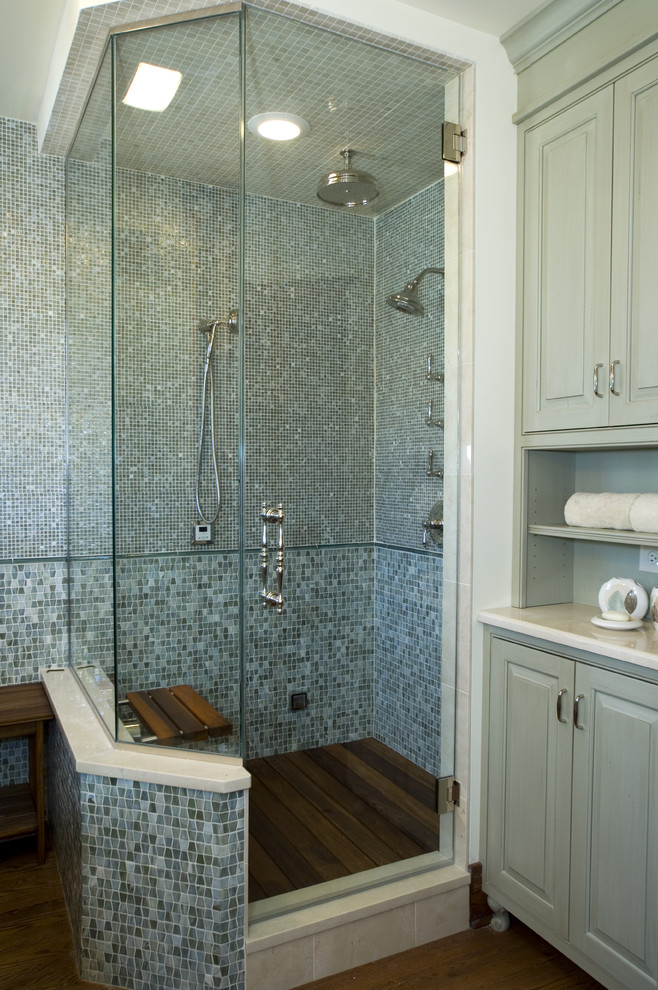 Cette photo montre une salle de bain chic avec une douche d'angle, un carrelage bleu, mosaïque, parquet foncé et une cabine de douche à porte battante.