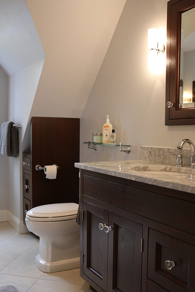 Diseño de cuarto de baño principal tradicional con armarios estilo shaker, puertas de armario de madera en tonos medios, sanitario de una pieza, paredes grises, suelo de baldosas de porcelana y ducha esquinera