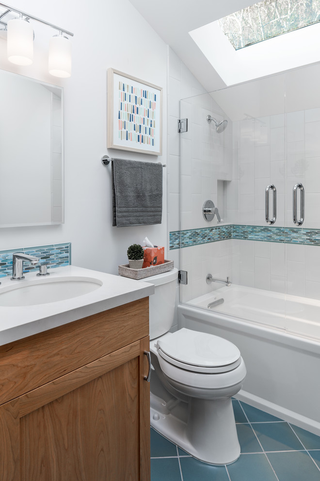 На фото: маленькая ванная комната в морском стиле с фасадами в стиле шейкер, ванной в нише, душем над ванной, раздельным унитазом, синей плиткой, полом из керамической плитки, врезной раковиной, столешницей из искусственного кварца, синим полом, душем с распашными дверями, фасадами цвета дерева среднего тона, плиткой мозаикой, белыми стенами и душевой кабиной для на участке и в саду