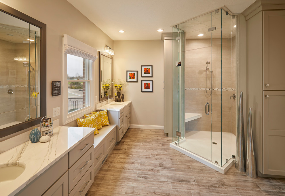 Inspiration for a classic ensuite bathroom in Indianapolis with recessed-panel cabinets, grey cabinets, a corner shower, beige tiles, beige walls, a submerged sink, brown floors, a hinged door and white worktops.