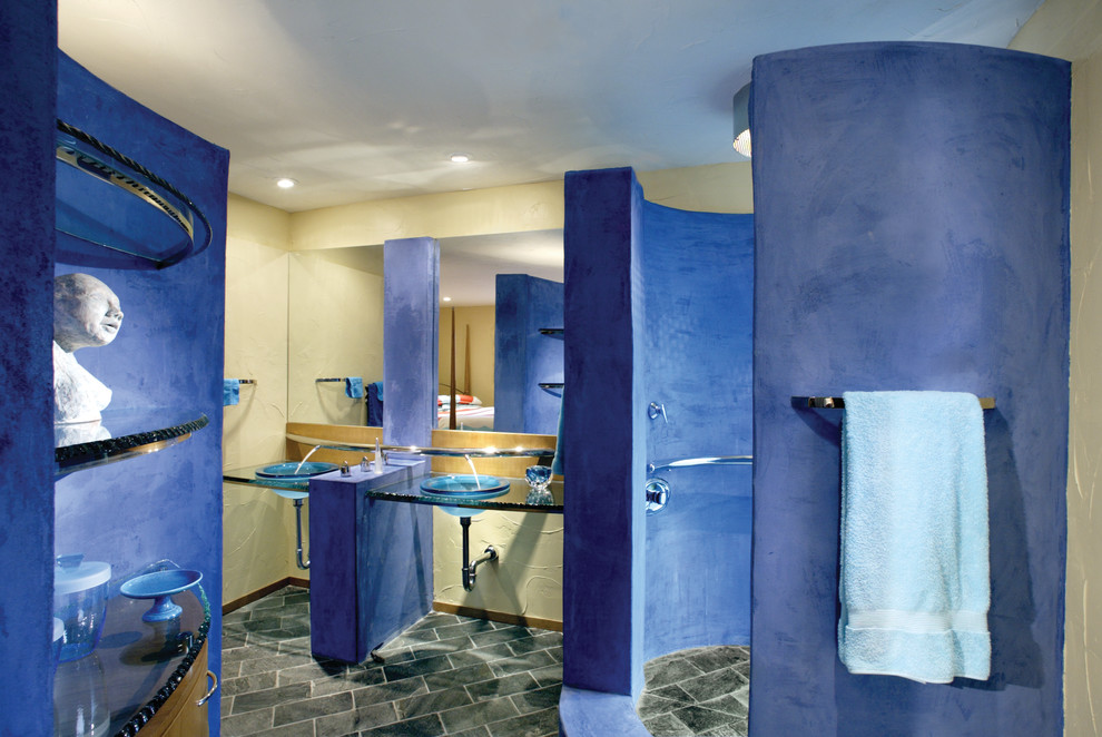 Cette photo montre une salle d'eau tendance avec un lavabo posé, un plan de toilette en verre, une douche d'angle et un mur bleu.