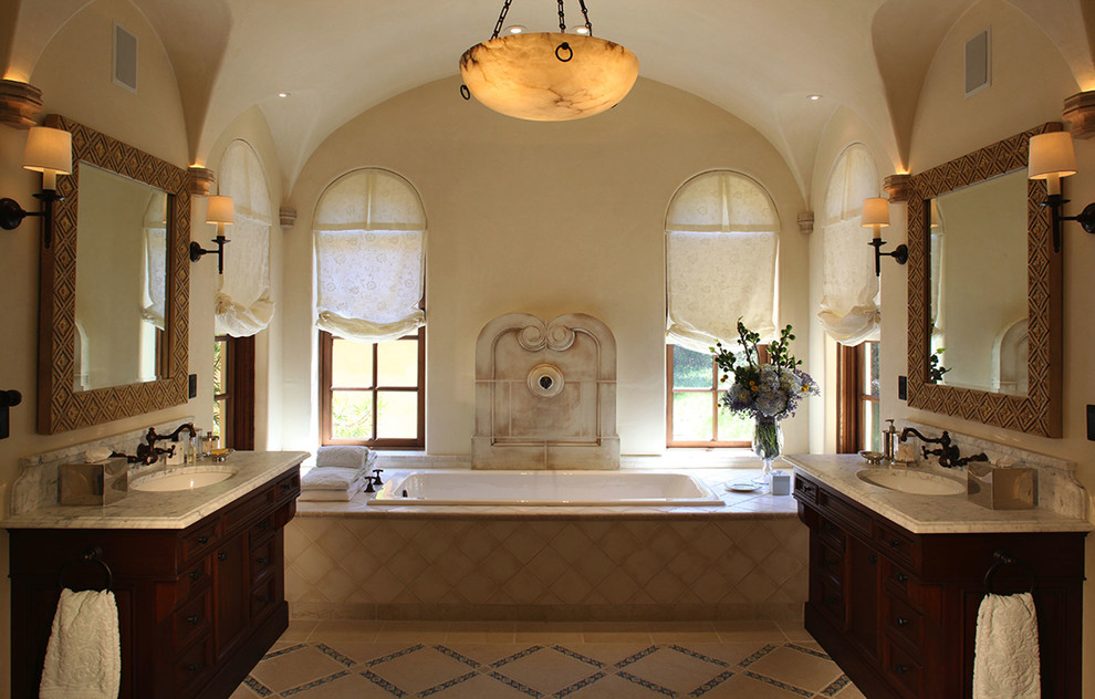 Exemple d'une grande salle de bain principale méditerranéenne en bois foncé avec un placard avec porte à panneau encastré, une baignoire posée, un carrelage marron, des carreaux de céramique, un mur marron, un lavabo encastré, un plan de toilette en marbre et un plan de toilette gris.