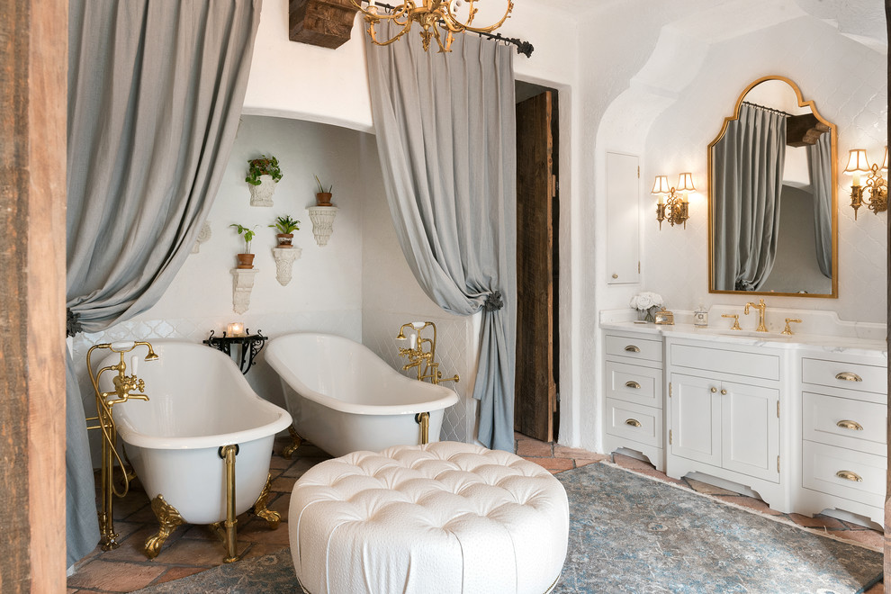 Cette photo montre une salle de bain principale méditerranéenne de taille moyenne avec un placard à porte shaker, des portes de placard blanches, une baignoire sur pieds, une douche d'angle, un carrelage blanc, des carreaux de porcelaine, tomettes au sol, un lavabo posé, un plan de toilette en marbre et un mur blanc.