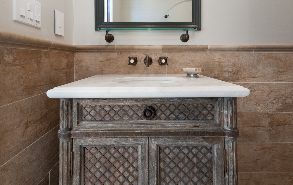 Cette image montre une salle de bain méditerranéenne en bois vieilli de taille moyenne avec des carreaux de porcelaine, sol en béton ciré, un plan de toilette en marbre, un carrelage beige, un mur beige et un lavabo encastré.