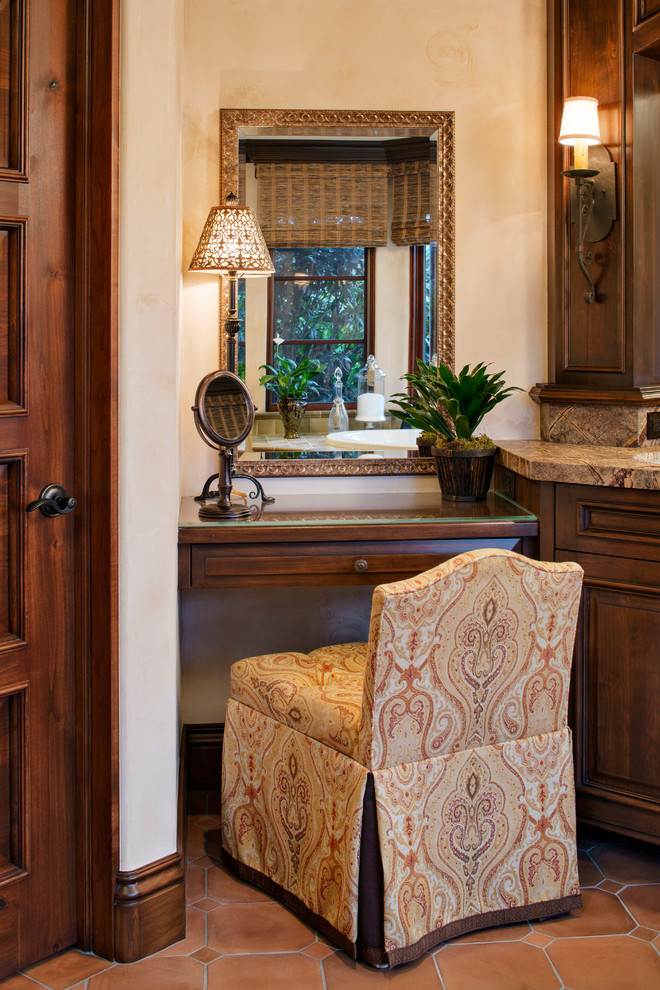 Immagine di una stanza da bagno padronale mediterranea di medie dimensioni con lavabo sottopiano, consolle stile comò, ante in legno bruno, top in marmo, vasca da incasso, pavimento in terracotta e pareti beige