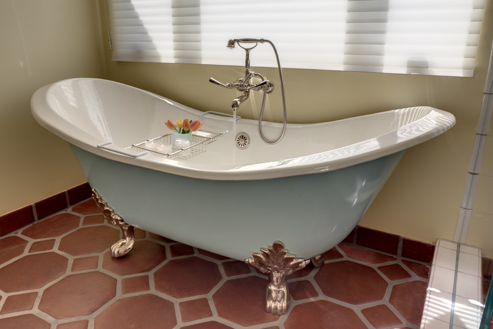 Modelo de cuarto de baño principal mediterráneo de tamaño medio con bañera con patas, ducha empotrada, paredes amarillas y suelo de baldosas de terracota
