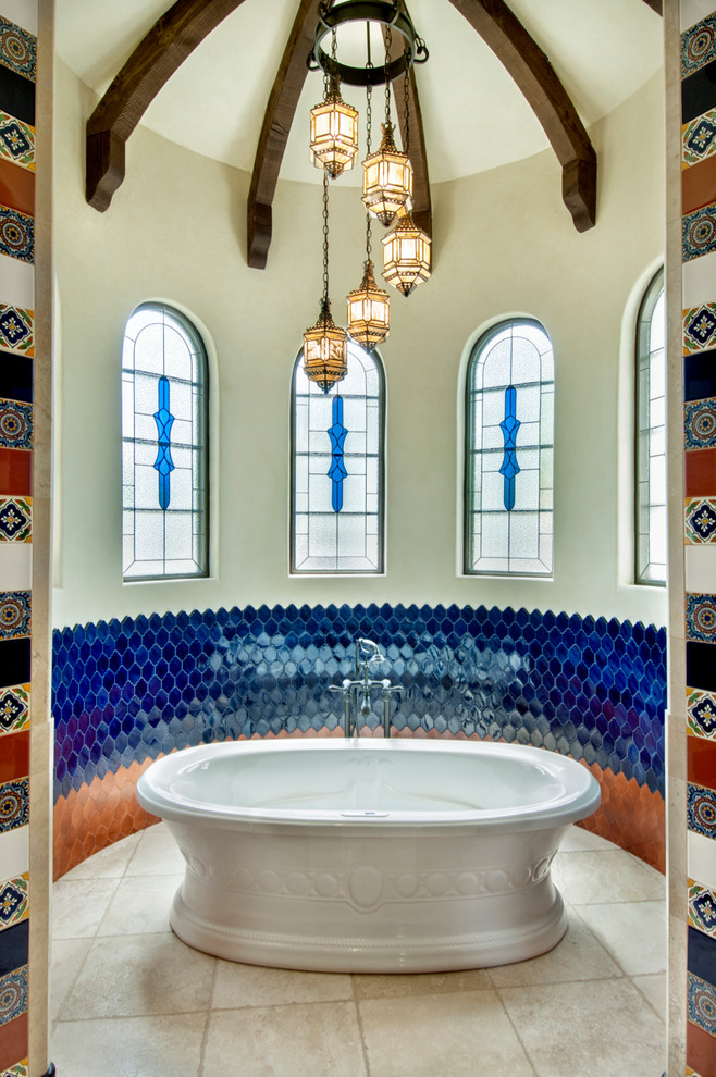 ヒューストンにある地中海スタイルのおしゃれなマスターバスルーム (置き型浴槽、青いタイル、マルチカラーのタイル、オレンジのタイル、ベージュの床) の写真