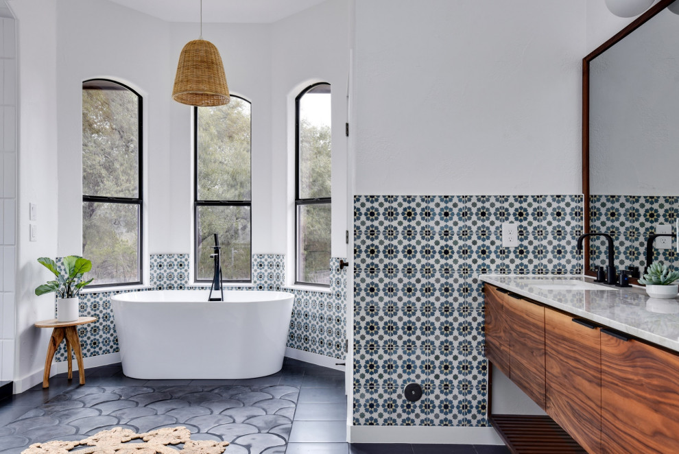 На фото: ванная комната в средиземноморском стиле с плоскими фасадами, фасадами цвета дерева среднего тона, отдельно стоящей ванной, разноцветной плиткой, белыми стенами, врезной раковиной, серым полом, белой столешницей и подвесной тумбой
