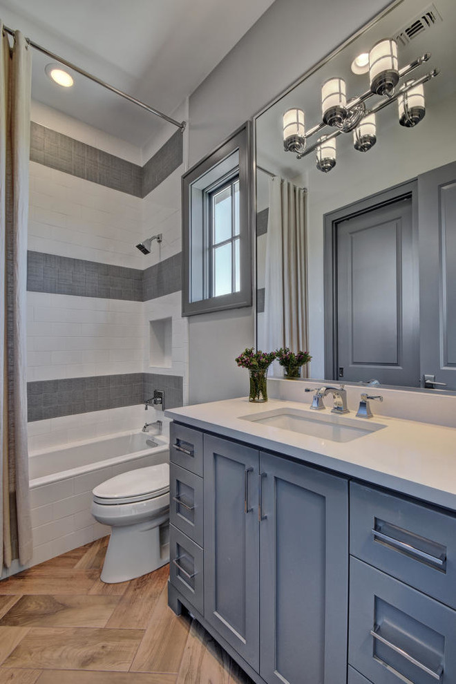 Inspiration for a large traditional family bathroom in Austin with shaker cabinets, grey cabinets, an alcove bath, a shower/bath combination, grey tiles, white tiles, grey walls, a submerged sink, brown floors, a shower curtain, a one-piece toilet, porcelain tiles, ceramic flooring, granite worktops and white worktops.