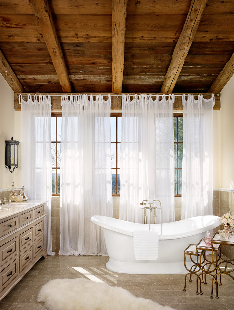 Diseño de cuarto de baño mediterráneo con puertas de armario grises, bañera exenta, baldosas y/o azulejos grises, paredes blancas y lavabo bajoencimera