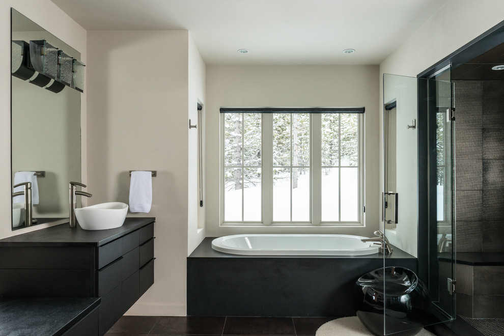 На фото: большая главная ванная комната в современном стиле с плоскими фасадами, столешницей из известняка, черными фасадами, накладной ванной, белыми стенами, настольной раковиной, душем с распашными дверями и окном