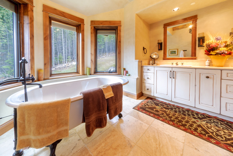 Foto på ett rustikt badrum, med ett nedsänkt handfat, luckor med upphöjd panel, vita skåp, ett badkar med tassar, vit kakel och stenkakel
