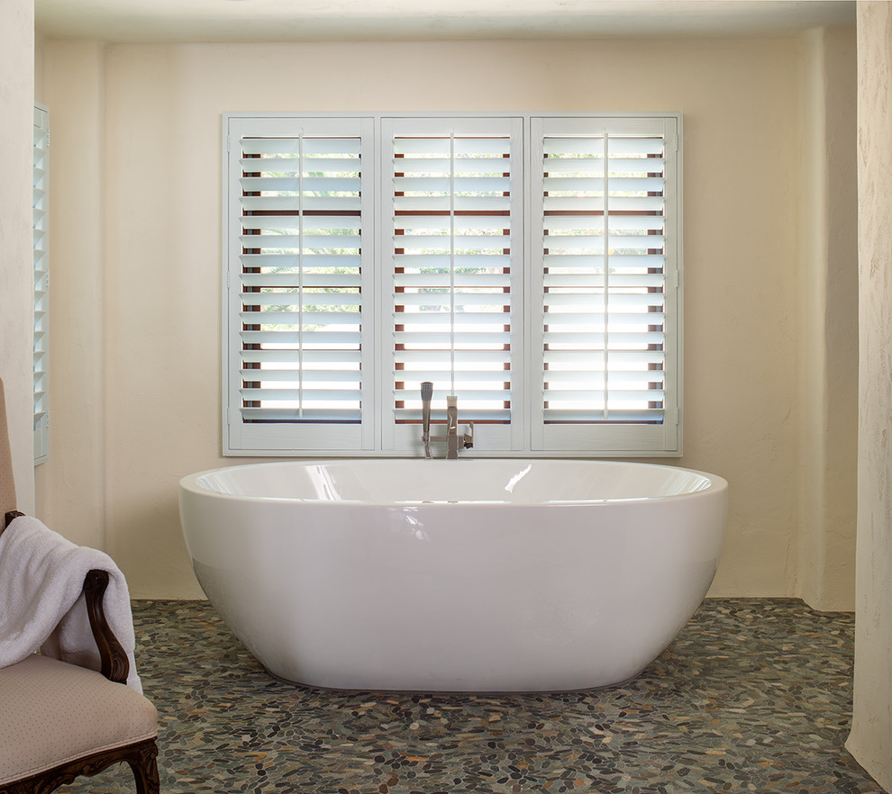 Diseño de cuarto de baño de estilo americano con bañera japonesa, paredes beige, suelo de baldosas tipo guijarro y suelo marrón
