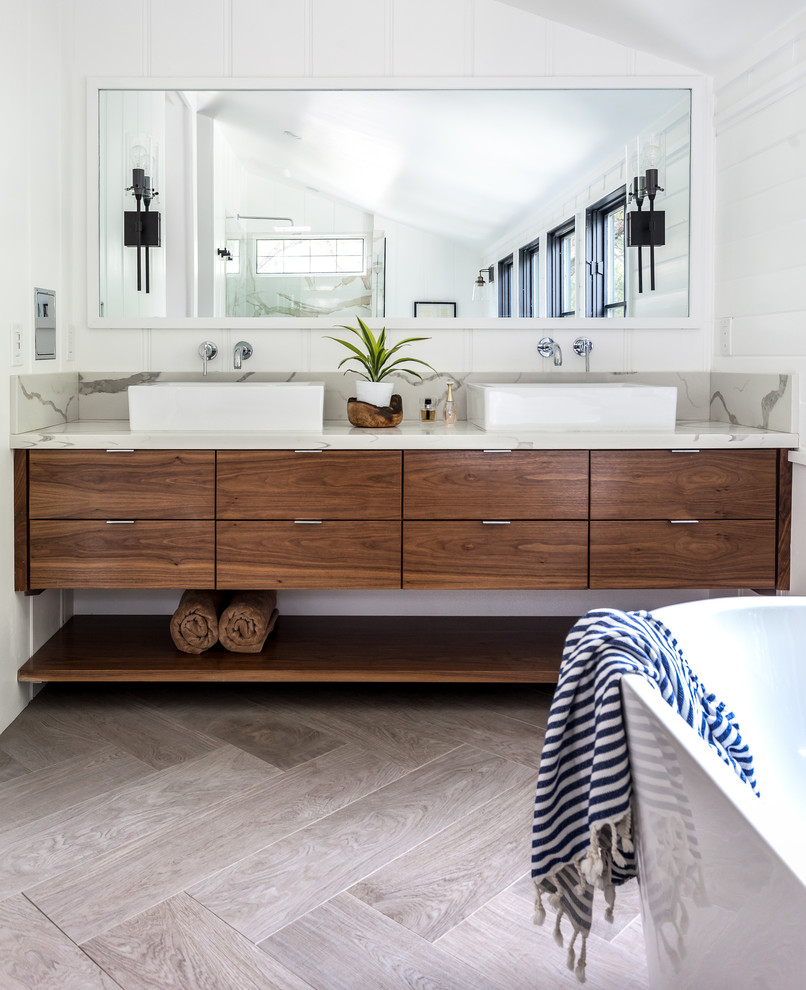 Mediterranean ensuite bathroom in Sacramento with medium wood cabinets, a freestanding bath, white walls, marble worktops, grey floors, flat-panel cabinets, a vessel sink and beige worktops.