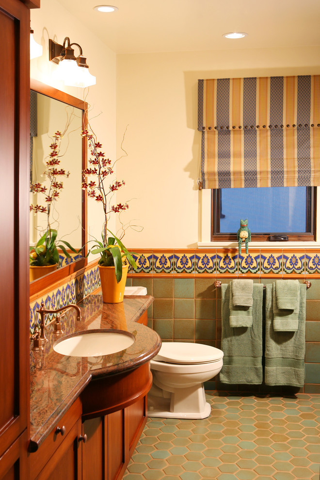 Diseño de cuarto de baño mediterráneo con lavabo bajoencimera, armarios estilo shaker, puertas de armario de madera oscura, baldosas y/o azulejos multicolor y suelo de baldosas de terracota