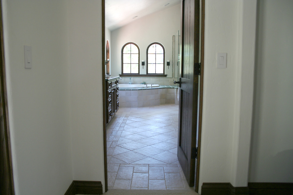 Aménagement d'une grande salle de bain principale méditerranéenne avec une baignoire posée, un carrelage beige, des portes de placard marrons et un sol en carrelage de porcelaine.