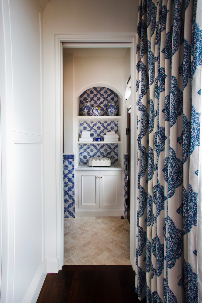 На фото: детская ванная комната среднего размера в средиземноморском стиле с фасадами с утопленной филенкой, белыми фасадами, полновстраиваемой ванной, душем над ванной, синей плиткой, керамической плиткой, белыми стенами, полом из известняка, врезной раковиной, мраморной столешницей, бежевым полом, душем с распашными дверями и белой столешницей с