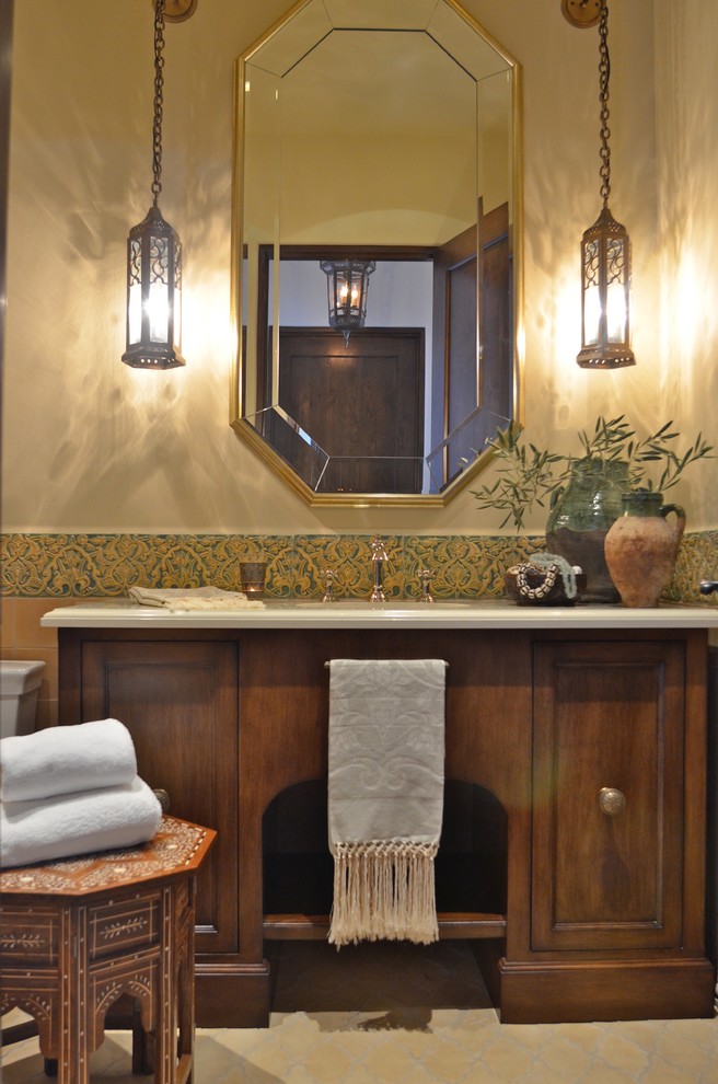 Exemple d'une salle de bain méditerranéenne de taille moyenne avec un placard avec porte à panneau encastré, des portes de placard marrons, un carrelage vert, des carreaux de céramique, un mur beige, sol en béton ciré, un lavabo encastré, un plan de toilette en calcaire, un sol multicolore et un plan de toilette beige.