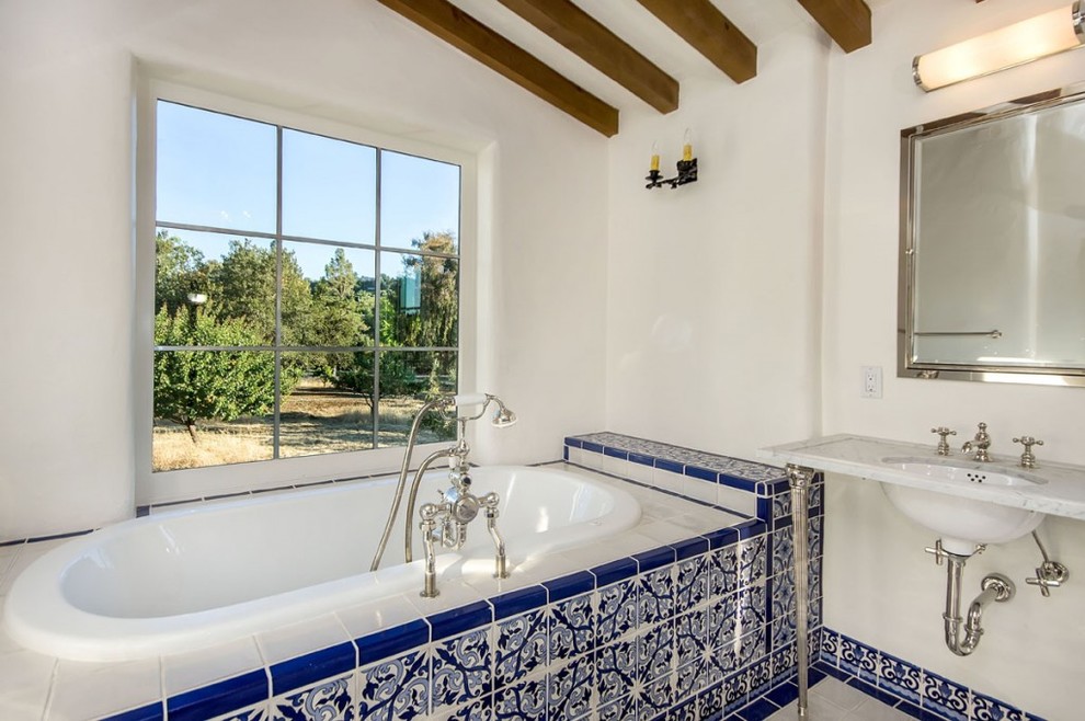 Immagine di una stanza da bagno mediterranea con top in marmo e lavabo a consolle