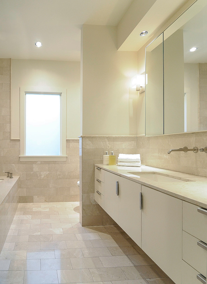 Bild på ett litet funkis en-suite badrum, med släta luckor, vita skåp, ett undermonterat badkar, en öppen dusch, en toalettstol med hel cisternkåpa, beige kakel, travertinkakel, vita väggar, travertin golv, ett undermonterad handfat, marmorbänkskiva, beiget golv och med dusch som är öppen