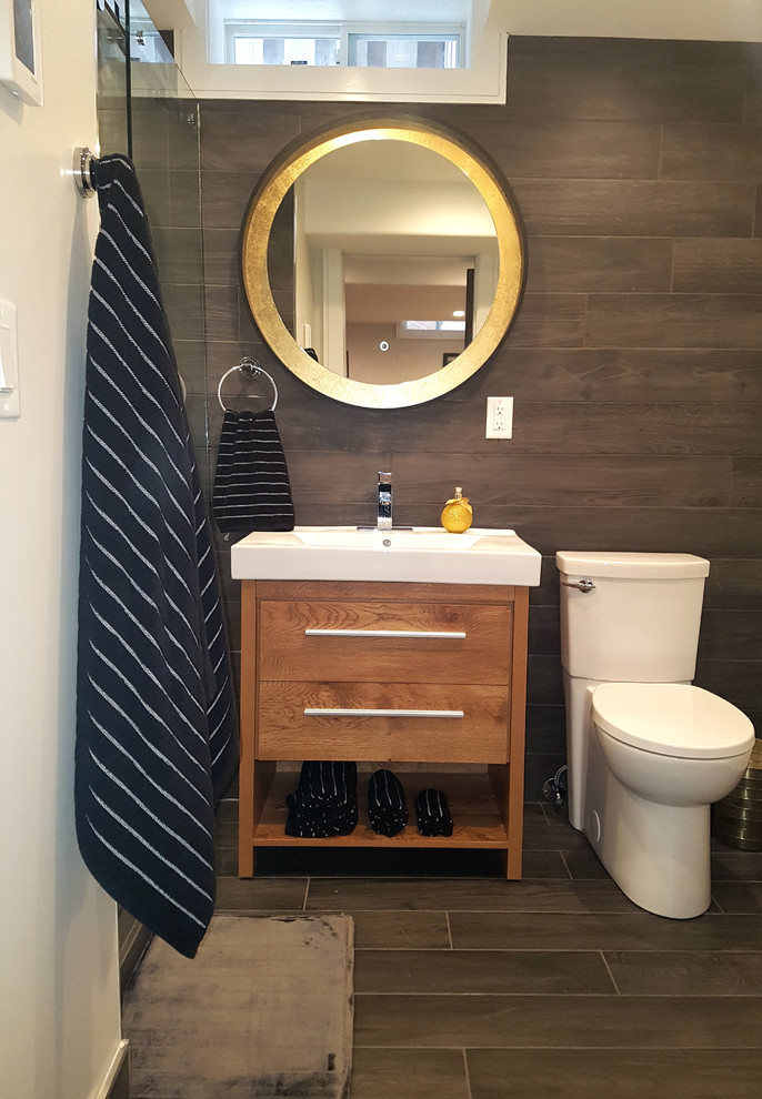 Mid-sized minimalist black tile and ceramic tile porcelain tile and black floor bathroom photo in Toronto with furniture-like cabinets, brown cabinets, a two-piece toilet, white walls, a vessel sink, solid surface countertops and white countertops