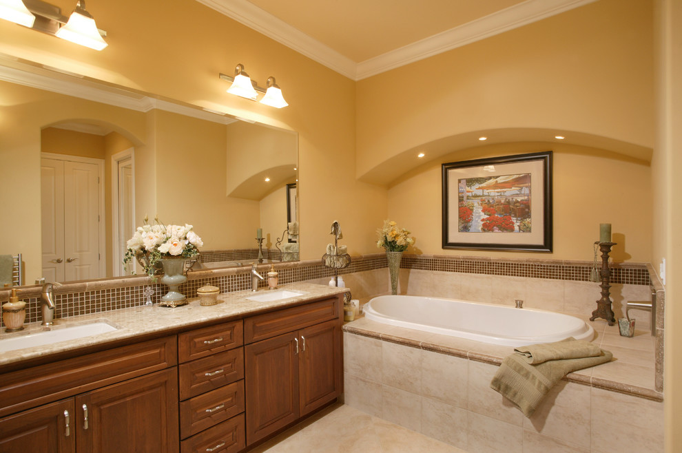 Modelo de cuarto de baño principal clásico con encimera de granito, bañera encastrada y paredes amarillas