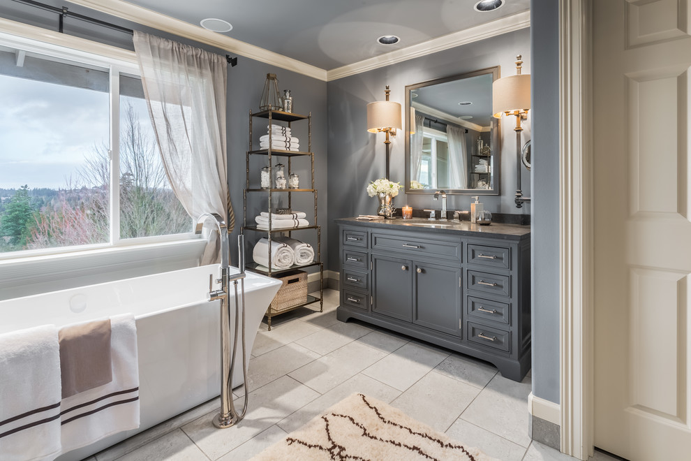 Design ideas for a large traditional ensuite bathroom in Seattle with freestanding cabinets, grey cabinets, a freestanding bath, a corner shower, grey walls, porcelain flooring, a submerged sink, grey floors and a hinged door.