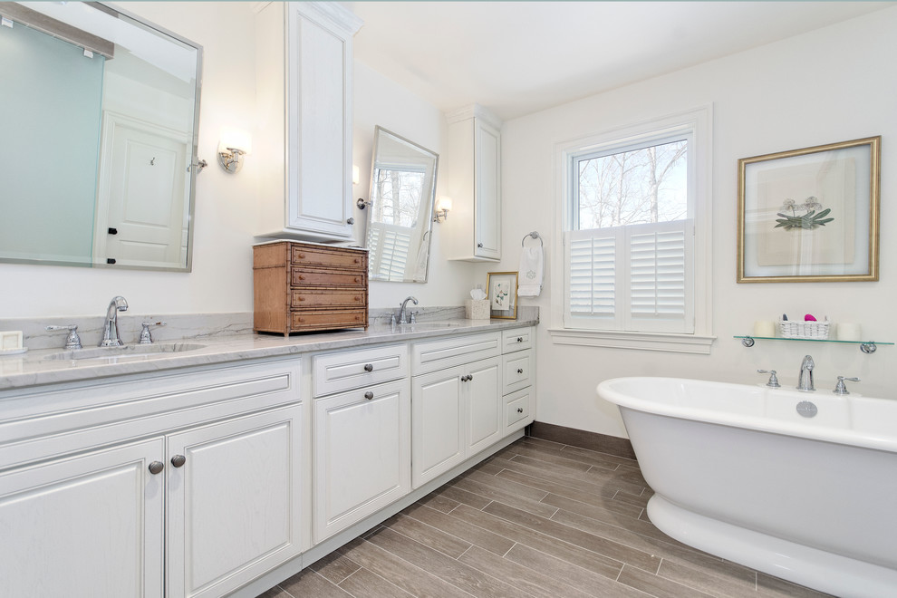 Foto på ett vintage badrum, med ett undermonterad handfat, luckor med upphöjd panel, vita skåp, marmorbänkskiva, ett fristående badkar, en hörndusch, en toalettstol med separat cisternkåpa, beige kakel och keramikplattor