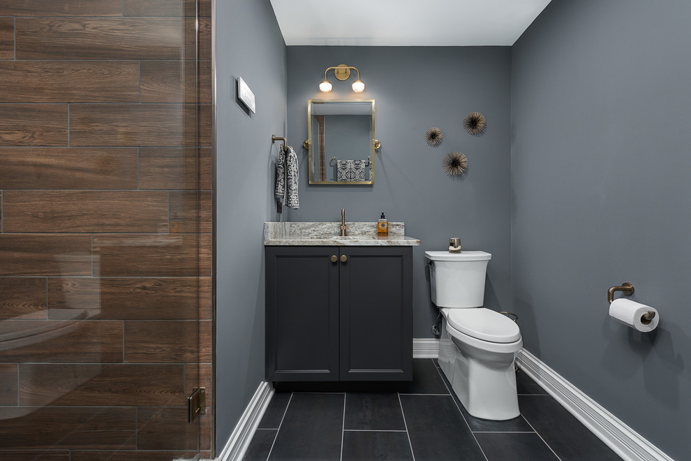 Exemple d'une grande salle de bain chic avec un carrelage marron, un sol gris, une cabine de douche à porte battante, un placard avec porte à panneau encastré, des portes de placard bleues, WC séparés, des carreaux de porcelaine, un mur bleu, un sol en carrelage de céramique, un lavabo encastré, un plan de toilette en granite et un plan de toilette gris.