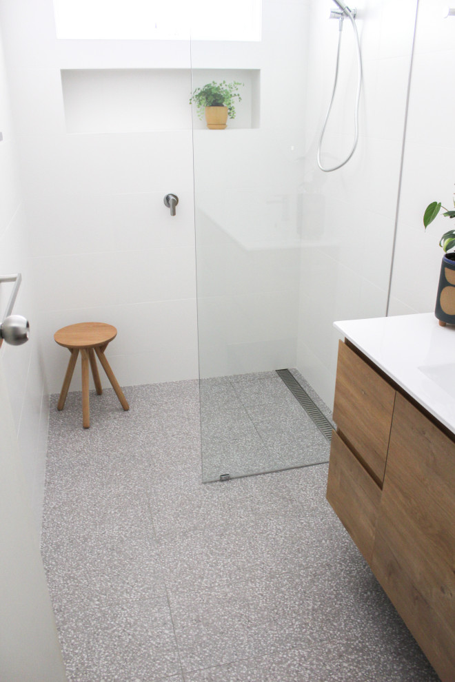 Exempel på ett mellanstort vit vitt badrum för barn, med släta luckor, skåp i mörkt trä, en öppen dusch, vit kakel, keramikplattor, vita väggar, terrazzogolv, ett integrerad handfat, bänkskiva i akrylsten, grått golv och med dusch som är öppen