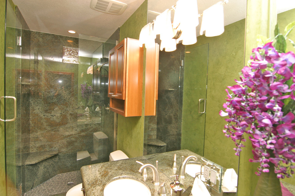 Cette photo montre une douche en alcôve principale exotique de taille moyenne avec un carrelage multicolore, des dalles de pierre, un mur vert, un lavabo encastré, un plan de toilette en granite et une cabine de douche à porte battante.