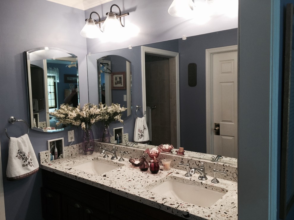 Modelo de cuarto de baño clásico pequeño con puertas de armario de madera en tonos medios, paredes azules, aseo y ducha, lavabo bajoencimera, encimera de vidrio reciclado, bañera esquinera, ducha abierta, sanitario de una pieza, baldosas y/o azulejos en mosaico y suelo de madera oscura