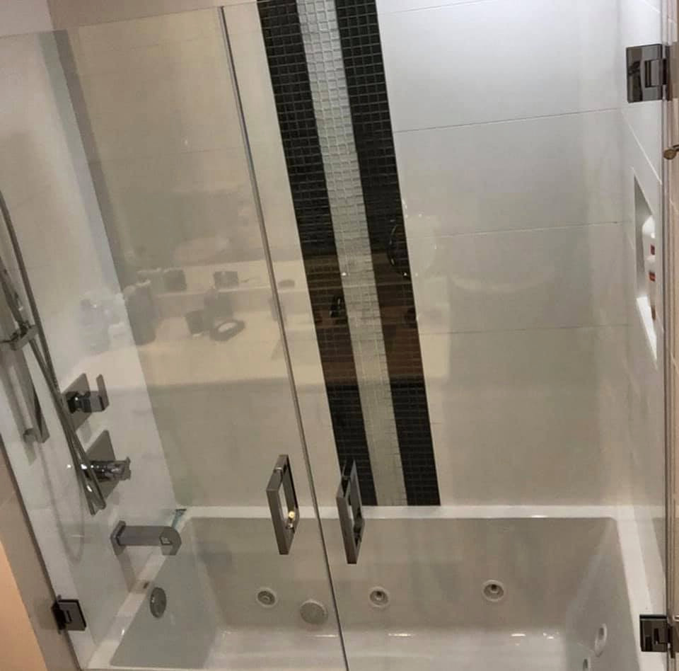 Immagine di una stanza da bagno moderna con vasca idromassaggio, vasca/doccia, piastrelle bianche, piastrelle in gres porcellanato, pareti bianche e porta doccia a battente