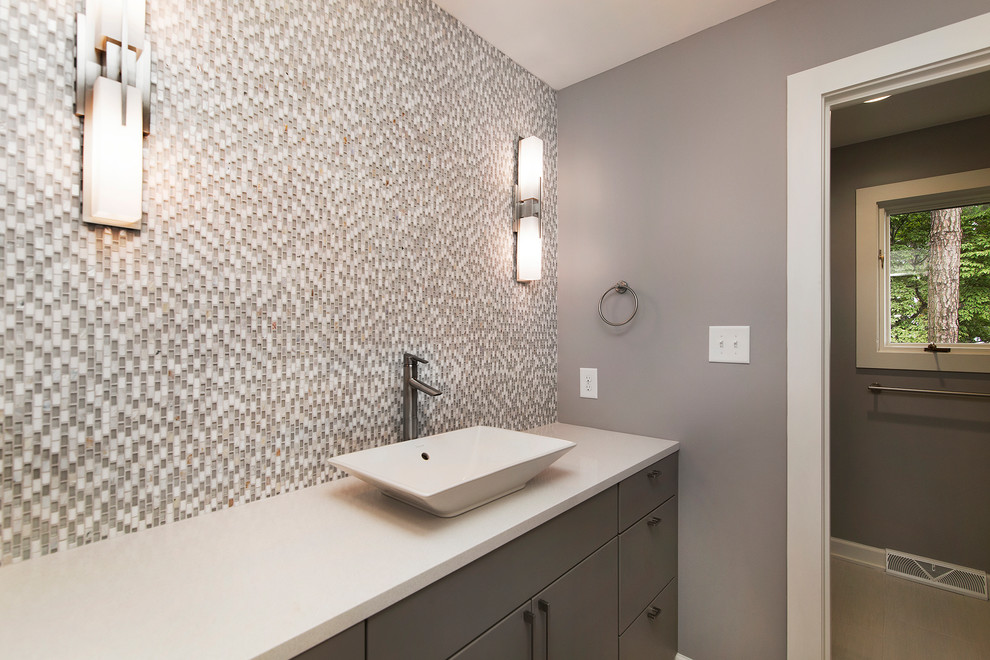 Idée de décoration pour une petite salle de bain minimaliste en bois brun avec une vasque, un placard à porte plane, un plan de toilette en surface solide, WC à poser, un carrelage gris, un carrelage en pâte de verre, un mur gris et un sol en carrelage de céramique.