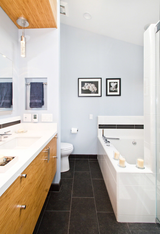 Aménagement d'une salle de bain contemporaine en bois clair avec un placard à porte plane.