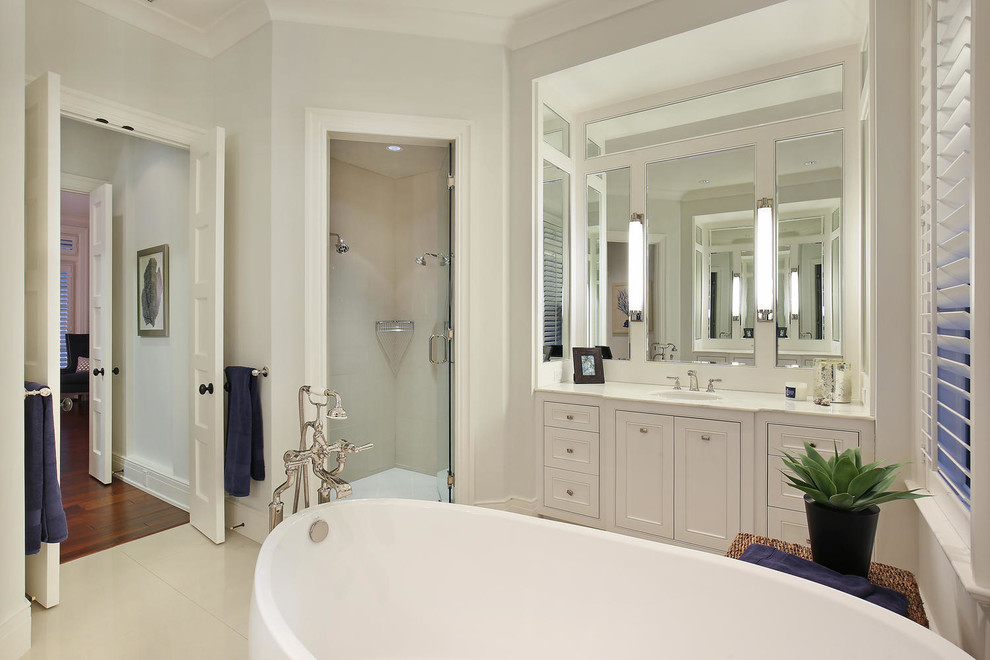 Exemple d'une grande salle de bain principale exotique avec un placard avec porte à panneau encastré, des portes de placard blanches, une baignoire indépendante, une douche d'angle, WC séparés, un carrelage beige, des carreaux de céramique, un mur blanc, un sol en carrelage de porcelaine, un lavabo encastré et un plan de toilette en marbre.