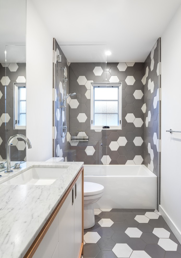 Foto på ett badrum med dusch, med släta luckor, vita skåp, en dusch/badkar-kombination, vita väggar, ett undermonterad handfat, marmorbänkskiva, grått golv och med dusch som är öppen